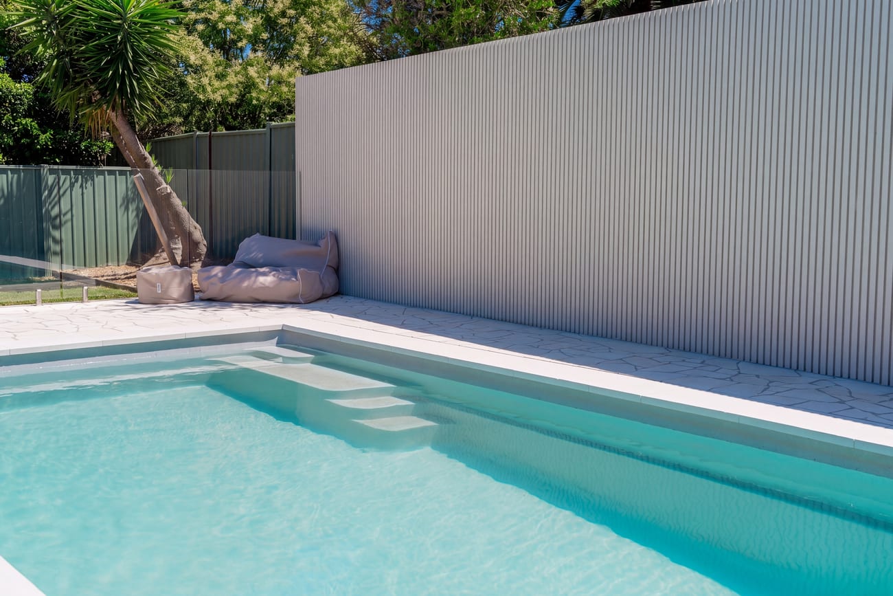 A lap pool set against a white corrugated screen wall